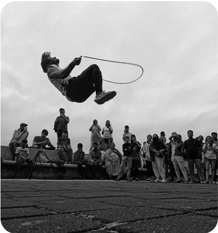 A man doing tricks with a rope in front of a crowd.