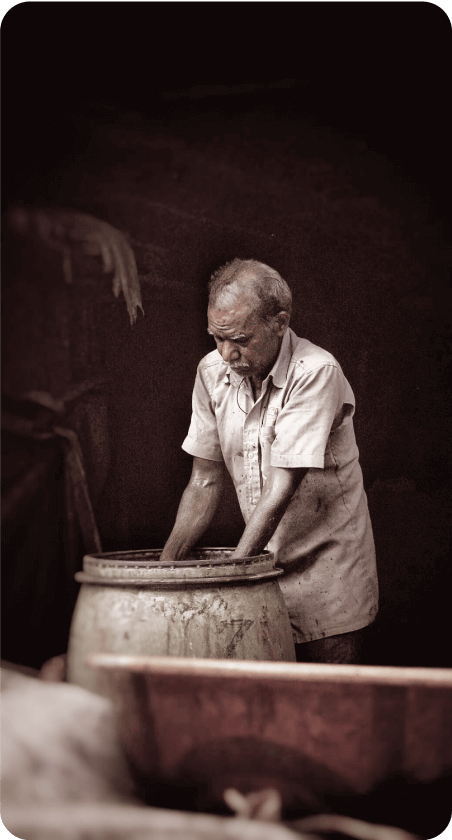 An old man pouring water into a pot.