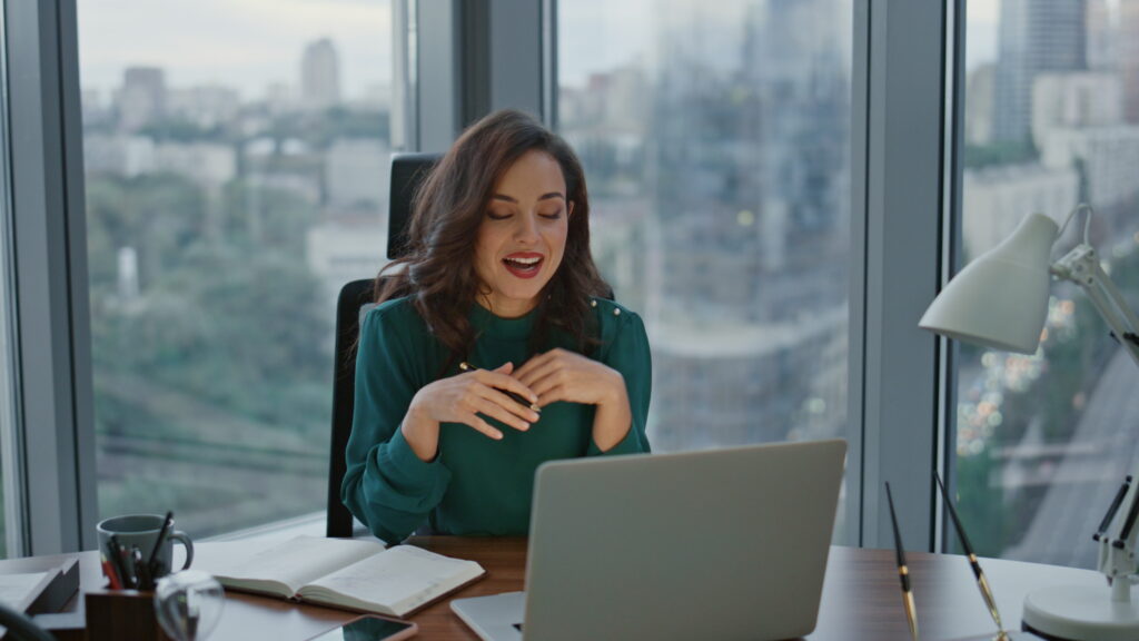 Brunette ceo talking on online conference using internet connection sitting at luxury office. Attractive business woman conducting business video meeting. Lady boss explaining work issues to webcam