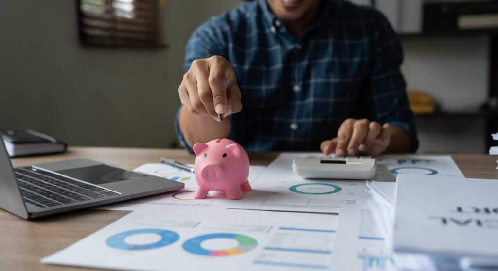 Happy man hand putting money coin into piggy for saving money wealth and financial accounting concept.