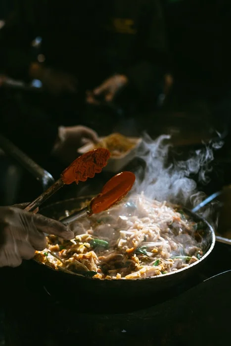 Steam coming out while a person is making a dish in a tawa